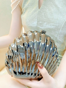 Detailed view of silver shell-shaped evening clutch with glossy metallic texture
