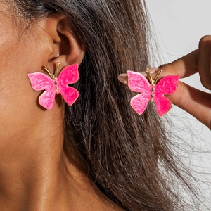 Gros plan détaillé des boucles d'oreilles papillon roses aux bords dorés de style doux
