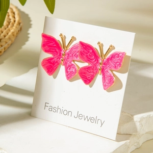 Gros plan de boucles d'oreilles papillon roses avec cadre doré sur carte mode