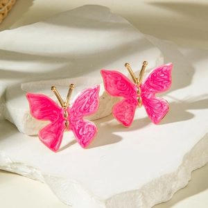 Boucles d'oreilles papillon en émail rose et bordure dorée sur un socle en pierre