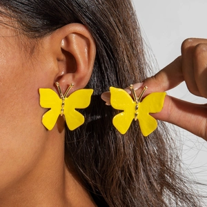 Vue détaillée des boucles d'oreilles papillon en émail jaune vif avec accents dorés