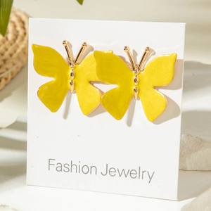 Gros plan de boucles d'oreilles papillon jaune vif avec bordures dorées sur présentoir