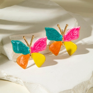 Boucles d'oreilles papillon colorées dorées sur des pierres blanches texturées
