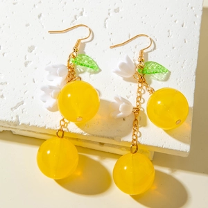 Macro detail of cherry earrings with yellow beads, white flowers and green leaves