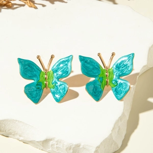 Détail de boucles d'oreilles papillon colorées avec émail sur pierre blanche