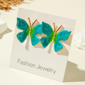 Détail de boucles d'oreilles papillon colorées avec bords dorés sur carte