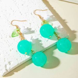 Detail view of acrylic cherry earrings with lily of the valley and gold hooks