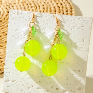 Close-up of summer cherry earrings with fluorescent beads and green leaf charm