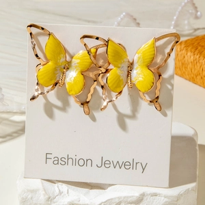 Détail de boucles d'oreilles papillon en émail jaune sur un support en pierre