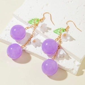 Close-up of purple cherry earrings with white lily of the valley and green leaf detail