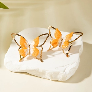 Détail de boucles d'oreilles papillon avec finition dorée et émail coloré vibrant