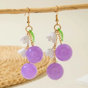 Elegant lily of the valley earrings with purple berries and gold hooks on wooden branch