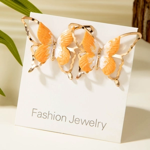 Vue détaillée des boucles d'oreilles papillon dorées avec émail marbré orange vif