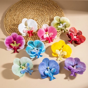 Flat lay of artificial orchid heads in 10 vivid colors on a natural woven mat background