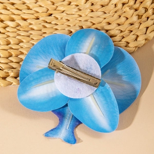 Detail view of the silver crocodile clip attached to the blue orchid hair flower