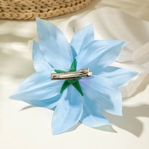 Detail of light blue lily flower hair clip with silver metal alligator clamp on stone base