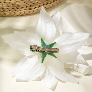 Detail of white fabric lily hair claw with green base and silver metal alligator clip