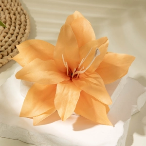 Close-up of artificial orange lily flower with detailed petals on white stone stand