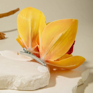 Close-up of realistic yellow lily hair clip with silk petals and silver metal alligator grip