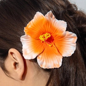 Macro view of a lifelike orange hibiscus flower hair clip worn by a model for beach style