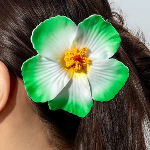 Macro shot of realistic green and white lily hair clip on model's dark hair