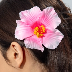 Detailed shot of a realistic pink gradient hibiscus hair clip on dark brown hair