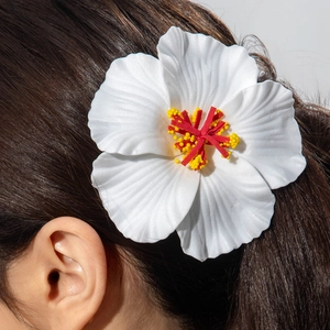 Detailed view of a white hibiscus hair clip styled on long dark hair for a beach look