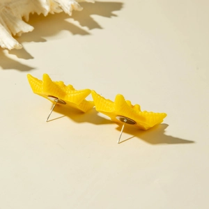 Detailed close-up of yellow resin starfish earrings on beige surface with white coral decor