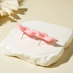 Detail of pink resin starfish earrings featuring unique textures on a textured stone slab