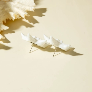 Macro detail of matte white starfish earring with natural shell texture on beige background