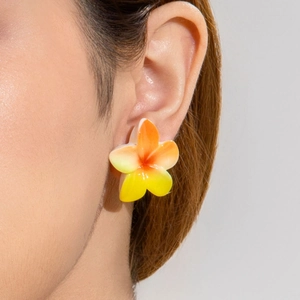 Detailed view of yellow and orange plumeria flower earring on a model ear
