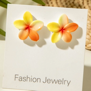Detailed close-up of yellow plumeria flower stud earrings on a fashion display card