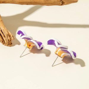 Detailed close-up of handmade purple daisy resin earrings on a natural wood background