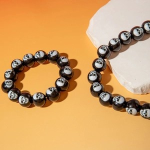 Close-up of black polished beads featuring white skull patterns for Halloween jewelry