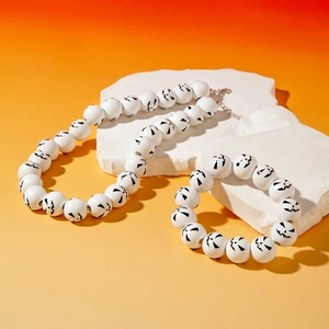 Close-up of Halloween pumpkin face beads on white necklace and bracelet set