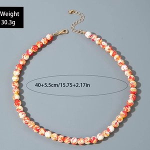 Detail of beaded Halloween necklace with orange splattered texture and gold lobster clasp