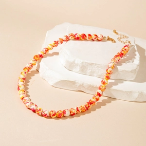 Macro shot of colorful paint-splattered beaded necklace on white stone display