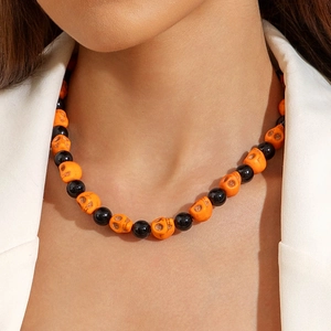 Detail of Halloween beaded necklace with orange resin skulls and polished black round beads