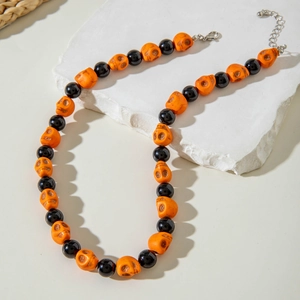 Detail of Halloween necklace with orange skull beads and black glossy pearls on stone