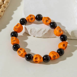 Detail of Halloween beaded bracelet featuring orange skull charms and black round beads