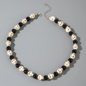 Detail of beaded necklace featuring black glossy beads and skull shapes with lobster clasp