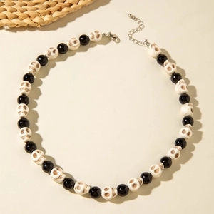 Close-up of Halloween necklace with black beads, white skull charms and metal clasp