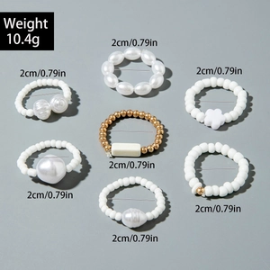 Detailed view of a 7-piece elastic bead ring set with pearls and floral charms