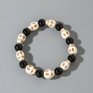 Detail of gothic beaded bracelet with black shiny beads and vintage skull charms