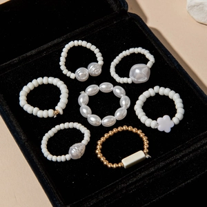 Detailed close-up of 7-piece pearl and gold bead ring set in a black velvet jewelry box