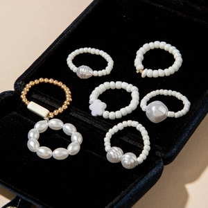 Detailed view of white pearls and gold bead rings set displayed in a black velvet box