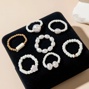 Detailed set of 7 pearl and gold beaded rings on black velvet jewelry display