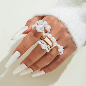 Bohemian pearl and turquoise cross ring set with white acrylic beads on a model's hand