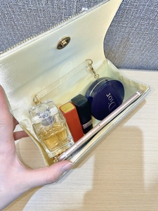 Dettaglio della pochette glitterata oro con fodera in raso e tracolla a catena interna