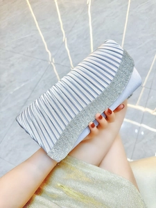 Detail of light blue satin evening clutch bag with pleated texture and rhinestone trim